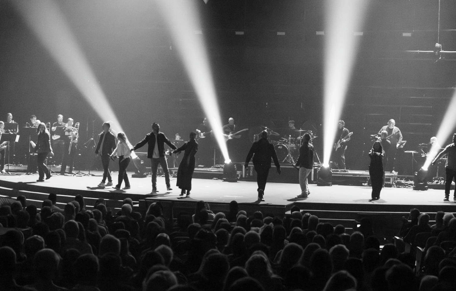 Great Joy — performers crossing the stage under white beam shafts